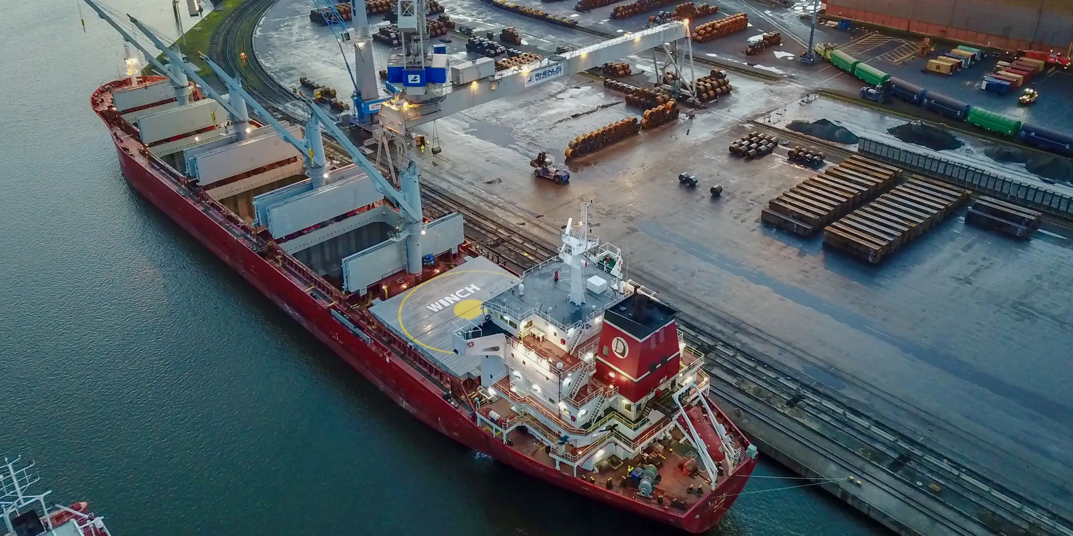 Dry bulk cargo loading operation on a modern bulk carrier, hatch covers open and port cranes working.