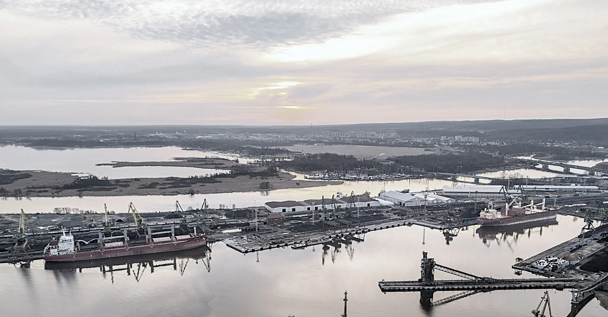 Maritime infrastructure and a modern bulk carrier in a working port, wide and understated composition.